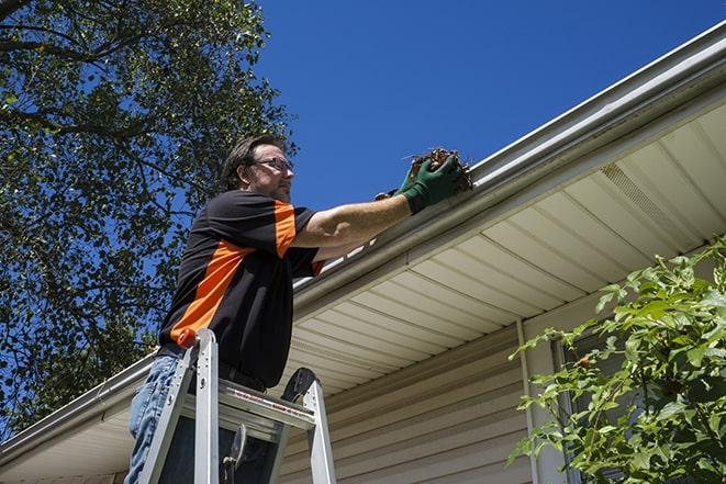 smiling worker fixing gutters on a residential home in Blanchard PA